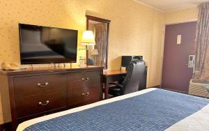 a hotel room with a bed and a desk with a television at Travelodge by Wyndham Seymour in Seymour