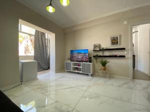 uma sala de estar com televisão e um grande piso de azulejo branco em Elegance to close from Lisbon! no Montijo