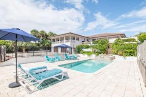 a swimming pool with two lounge chairs and an umbrella at Island Time -- Oceanfront Bliss in St. Augustine