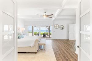 a white bedroom with a bed and a ceiling fan at Island Time -- Oceanfront Bliss in St. Augustine
