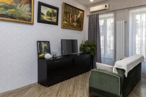 Una sala de estar con un televisor y una silla. en Old Town Italian Courtyard, en Tiflis
