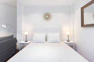 1 dormitorio con 1 cama blanca grande y 2 lámparas en Cálido apartamento. Tenerife. WiFi., en Arafo