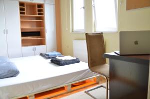 a room with a bed and a desk with a laptop at Center House Hostel in Prishtinë