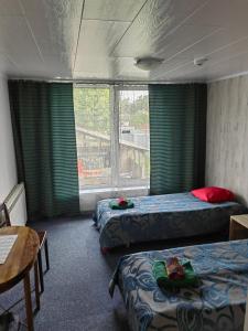 a room with two beds and a table and a window at Route House 39 Motel in Jõgeva
