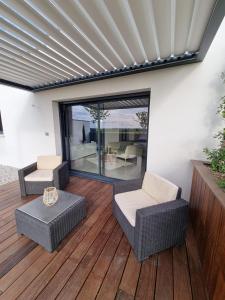 een patio met rieten meubels op een houten terras bij La Suite in Brie