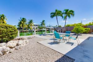 a patio with a table and chairs and palm trees at Downhome Cabin by the Canal in Key Colony Beach