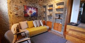 a room with a yellow couch in a stone wall at Castelinho in Raiva