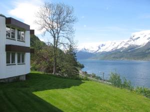 a house on a hill with a lake and mountains at Hardanger Hostel B&B in Lofthus