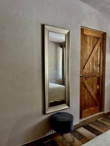 un espejo en una pared con un taburete al lado de una puerta en Cabañas Rancho San Jorge, en Bernal