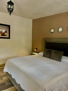 1 dormitorio con 1 cama blanca y 2 espejos en la pared en Cabañas Rancho San Jorge, en Bernal