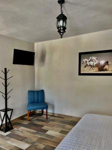 1 dormitorio con 1 cama y 1 silla azul en Cabañas Rancho San Jorge, en Bernal