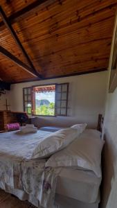 um quarto com uma cama grande e uma janela em Pousada Barriga da Lua em Serra do Cipó