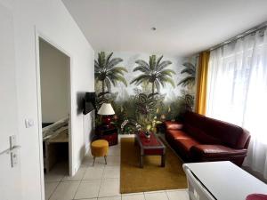 a living room with a couch and palm trees on the wall at Appartement avec extérieur in Loos