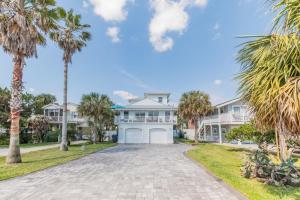 Una gran casa blanca con palmeras delante. en Seamora Ocean Hot Tub Firepit, en St. Augustine