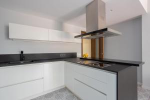a kitchen with white cabinets and a black counter top at Sunny Beachside Haven 2 Bd In The Marina District in Barcelona