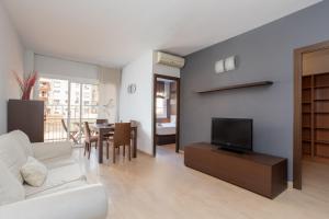a living room with a white couch and a television at Sunny Beachside Haven 2 Bd In The Marina District in Barcelona
