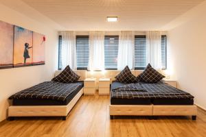 two beds in a room with windows at NECKARWESTHEIMER Appartement in Neckarwestheim