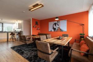 jadalnia z pomarańczowymi ścianami oraz stołem i krzesłami w obiekcie NECKARWESTHEIMER Appartement w mieście Neckarwestheim