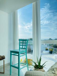 einem blauen Stuhl vor einem großen Fenster in der Unterkunft Tu Apartamento en Coronado in Chame