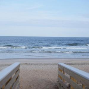 a bench sitting on the beach near the ocean at Casa Blanca Casita by the Ocean in St. Augustine