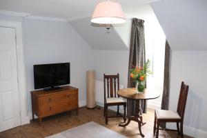 sala de estar con mesa y TV en The Loft at Craigmill House, en Blairgowrie