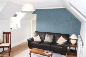 sala de estar con sofá de cuero negro y pared verde en The Loft at Craigmill House, en Blairgowrie