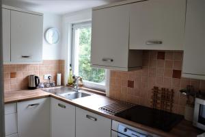 cocina con armarios blancos, fregadero y ventana en The Loft at Craigmill House, en Blairgowrie