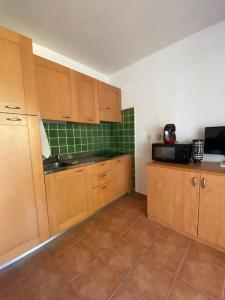 une cuisine avec des armoires en bois et un sol carrelé dans l'établissement Casa Emma les pieds dans l'eau, à San-Nicolao