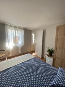 een slaapkamer met een groot bed en een blauw dekbed bij La Maison de Jeanne in Narbonne