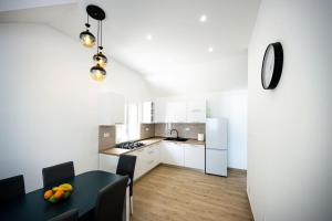 a kitchen with a black table and a kitchen with white cabinets at Kuća za odmor Farska in Nerežišće