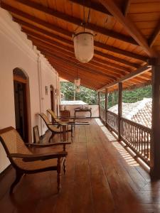 a patio with tables and chairs on a wooden deck at Elpitiya Walauwa Heritage Home in Gampola