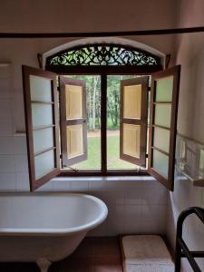 a bathroom with a window and a bath tub at Elpitiya Walauwa Heritage Home in Gampola