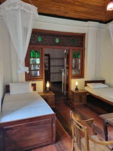 a bedroom with two beds and a table and chairs at Elpitiya Walauwa Heritage Home in Gampola