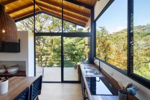 a kitchen with large windows and a view of the forest at Casas Jaguar in Monteverde Costa Rica