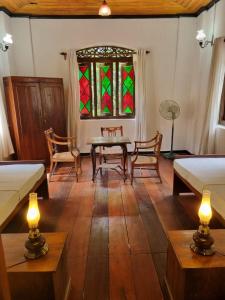 a room with two beds and a table and a stained glass window at Elpitiya Walauwa Heritage Home in Gampola