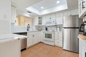 a kitchen with white cabinets and a stainless steel refrigerator at Beach Break Ocean Front Complex Beach Pool in Saint Augustine