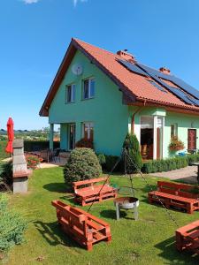 ein grünes Haus mit Bänken davor in der Unterkunft Dom Na Skarpie in Wałbrzych