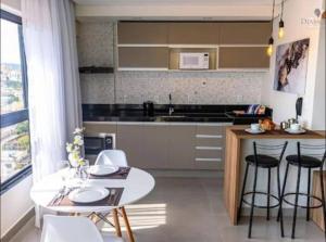 a kitchen with a white table and chairs and a counter at Flat lindo com piscina e linda vista da cidade in São Lourenço