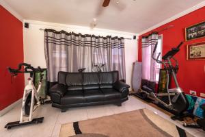 a living room with a black leather couch and exercise bikes at JAG Guesthouse- Little Bay Country Club in Negril