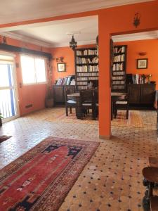 ein Wohnzimmer mit orangefarbenen Wänden und einem Teppich in der Unterkunft AZAWAN HOUSE in Tamraght Ouzdar