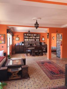 ein Wohnzimmer mit orangefarbenen Wänden, einem Sofa und einem Tisch in der Unterkunft AZAWAN HOUSE in Tamraght Ouzdar