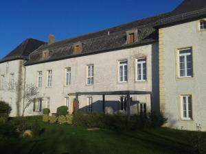 un grand bâtiment en briques blanches avec un toit noir dans l'établissement Le Chateau de Buchy, à Buchy