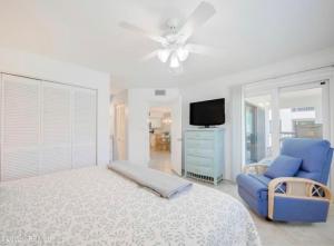 um quarto com uma cama e uma cadeira azul e uma televisão em Oasis 21 Oceanfront with Pool em Saint Augustine