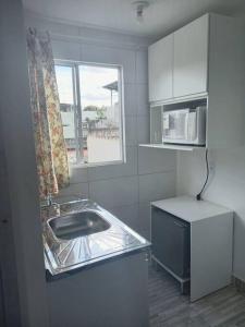 Apartamento Vila Telebrasilia في برازيليا: مطبخ صغير مع حوض ونافذة
