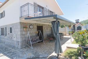 a patio with an umbrella and a balcony at Spacious villa for 10 with a big private pool in Trilj