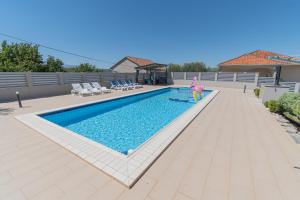 a person is standing next to a swimming pool at Spacious villa for 10 with a big private pool in Trilj