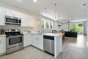 a kitchen with white cabinets and appliances and a living room at Treehouse By the Sea in St. Augustine