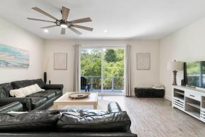a living room with a black leather couch and a ceiling fan at Treehouse By the Sea in St. Augustine