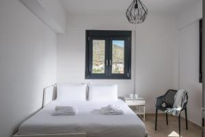 a white bedroom with a bed and a chair at Luxury Villa Marelina in Hersonissos +17 photos