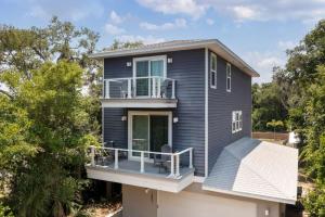 a blue house with a porch and a balcony at Treehouse By the Sea in St. Augustine